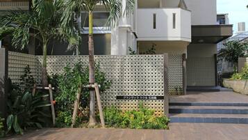 A modern building with a white facade, a wooden fence, and a palm tree.