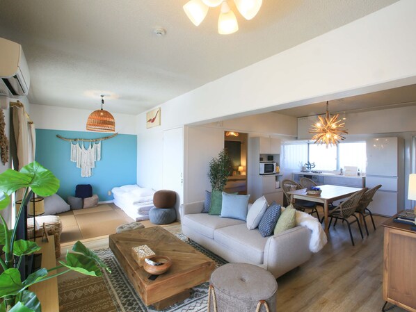 A modern living room with a sofa, coffee table, and a dining area with chairs and a table.
