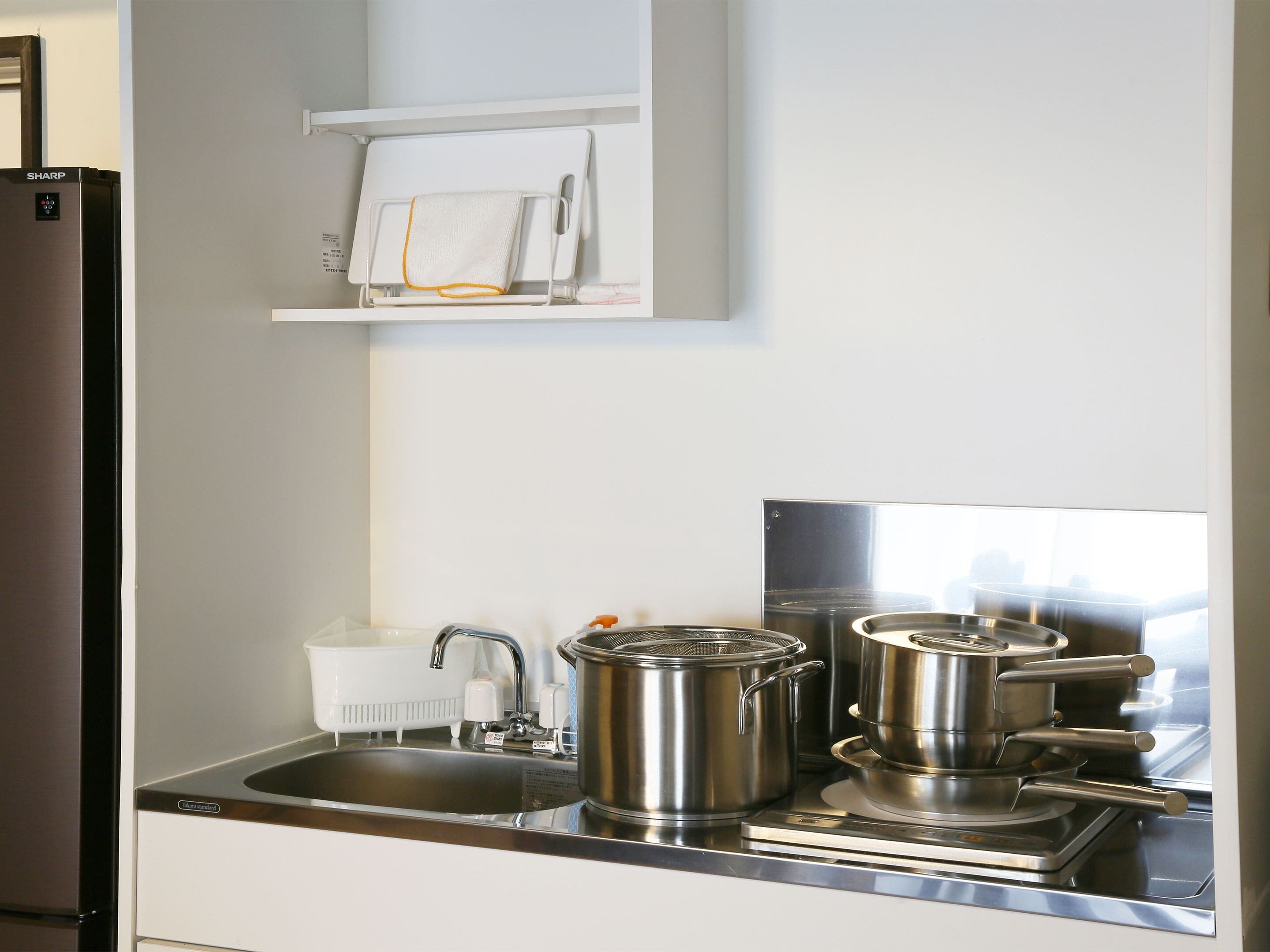 A modern kitchen with stainless steel appliances, a sink, and a shelf with a towel.