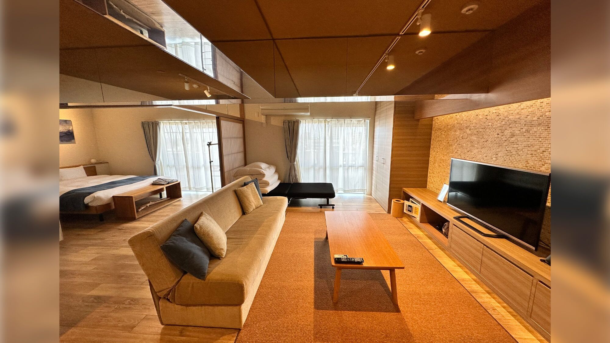 Un salon moderne avec un canapé, un banc, un téléviseur et un mur en briques.