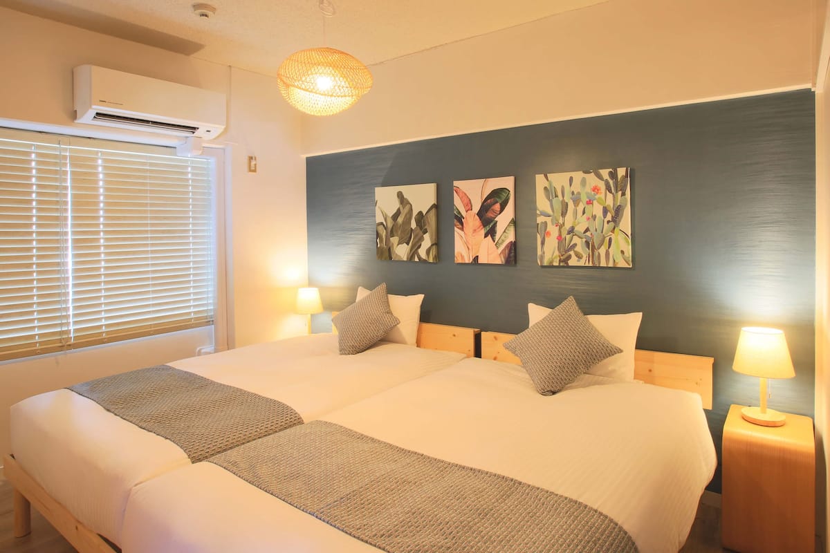 A hotel room with a large bed, two bedside lamps, a ceiling fan, and artwork on the wall.