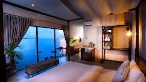 A bedroom with a large bed, a bench, a desk, and a view of the sea. - Tamarina Bed & Beyond (Koh Samui)