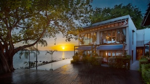 A modern house with a wooden deck overlooking a body of water at sunset. - Tamarina Bed & Beyond (Koh Samui)