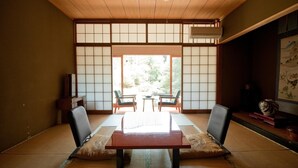 A traditional Japanese room with tatami flooring, a low wooden table, and sliding shoji doors. - Masuya Ryokan (Izumo)