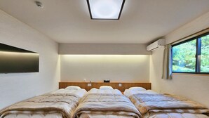 A room with a bed, a flat-screen TV, a ceiling light, and a window with a view of greenery. - Masuya Ryokan (Izumo)
