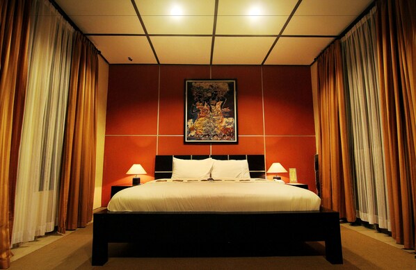 A hotel room with a large bed, two bedside tables with lamps, and a framed artwork on the wall. - Puri Chorus Hotel (Yogyakarta)
