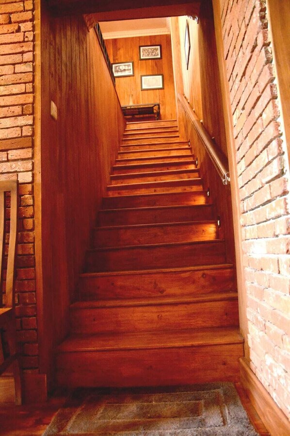 A wooden staircase with a handrail, leading to a landing with framed pictures on the wall. - The Rosedale Grand Nuwara Eliya (Nuwara Eliya)