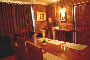 A dining area with a brick wall, wooden furniture, and a water dispenser. - The Rosedale Grand Nuwara Eliya (Nuwara Eliya)