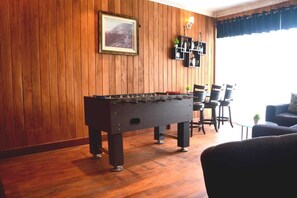 A room with a wooden wall, a foosball table, a framed picture, and a shelf with bottles. - The Rosedale Grand Nuwara Eliya (Nuwara Eliya)