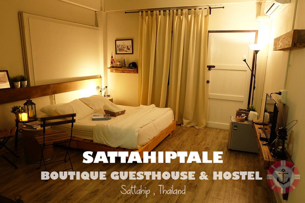 A cozy room with a bed, bedside table, lamp, and a small shelf with decorative items.