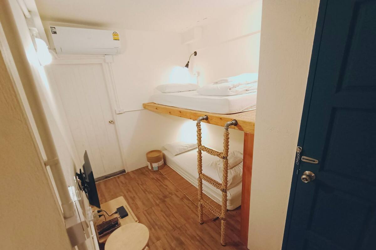 A small, compact room with a bunk bed, a small table, and a chair.