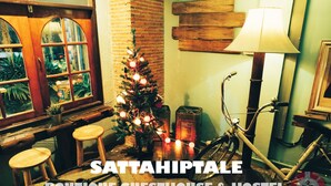 A cozy room with a Christmas tree, wooden stools, a bicycle, and a lamp. - Sattahiptale Boutique Guest House & Hostel (Sattahip)