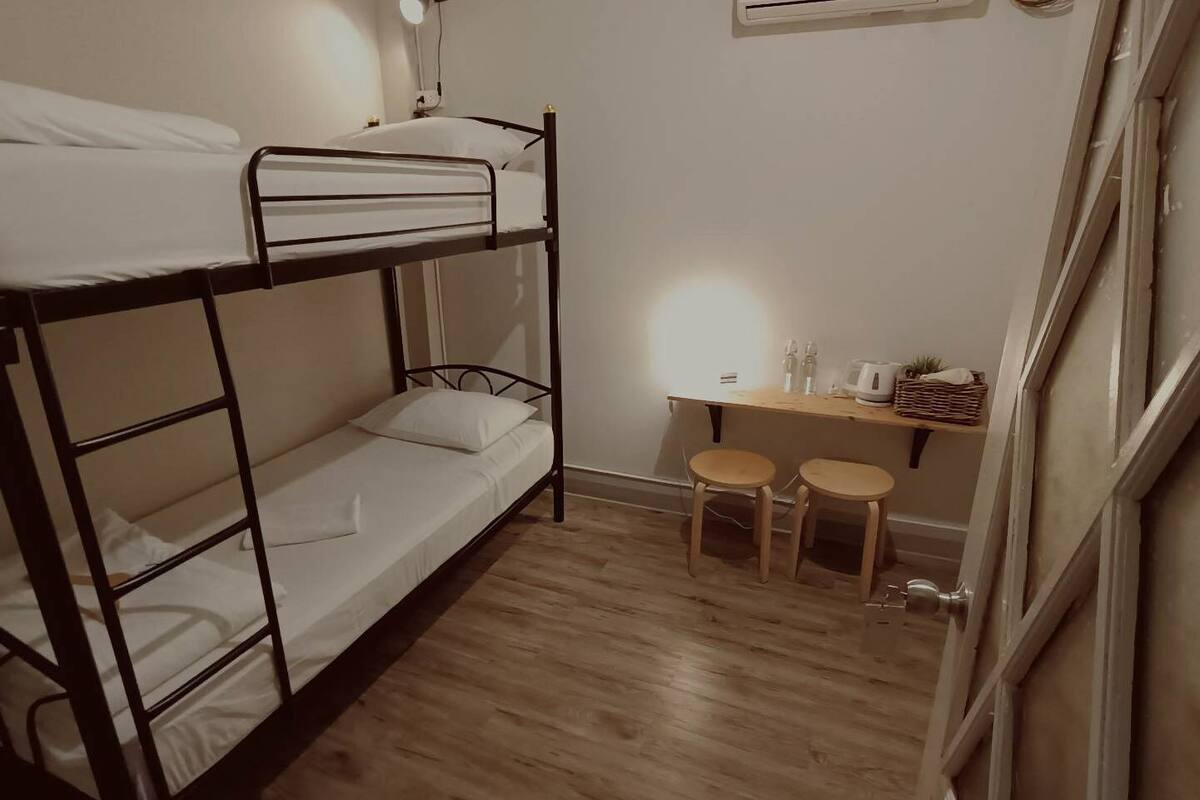 A bunk bed room with a desk and two stools.