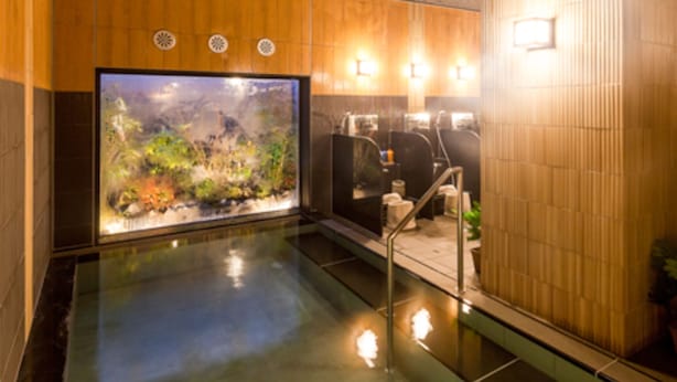 Un espace de bien-être doté d’un grand aquarium, de murs recouverts de panneaux en bois et d’un sol carrelé.