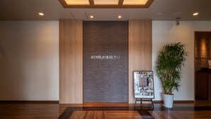 Un hall d’hôtel avec un plancher en bois, un comptoir d’accueil, une enseigne fixée au mur portant l’inscription « HOTEL ROUTE INN » et une plante en pot.