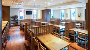 Un restaurant moderne avec des tables et des chaises en bois, un comptoir et une grande fenêtre qui laisse entrer la lumière naturelle.
