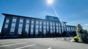 A hotel with a modern design, featuring a large parking lot and a clear sky. - Hotel Route - Inn Kumagaya (Kumagaya)