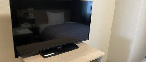 A flat-screen TV on a wooden TV stand in a hotel room.