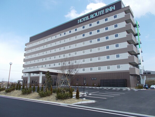 A multi-story hotel with a flat facade, numerous windows, and a parking lot in front.