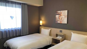 Habitación de hotel con dos camas, una mesita de noche con teléfono, una lámpara de pared y un cuadro.