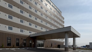 Un hotel moderno con entrada cubierta, varios pisos y estacionamiento.