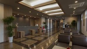 Un moderno vestíbulo de hotel con una recepción, una zona de estar y una cocina al fondo.