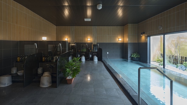 Un baño moderno con un espejo grande, varios lavamanos y una pequeña zona de piscina.