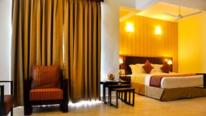 Une chambre d’hôtel avec un lit, une chaise, une petite table et un ventilateur de plafond.