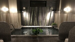 A spa area with a hot tub, bamboo plants, and stone seating. - Hotel Route Inn Fujichuokoen Higashi (Fuji)