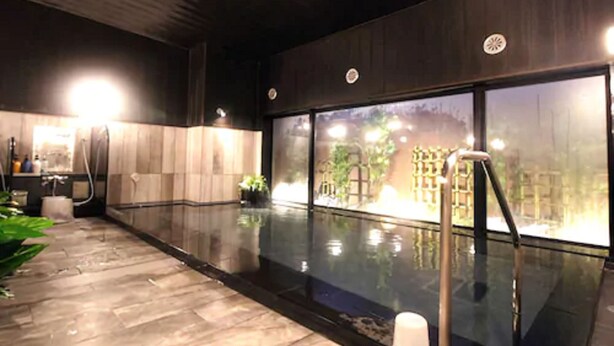 A modern indoor pool area with a glass wall, a sauna, and a wooden floor. - Hotel Route Inn Fujichuokoen Higashi (Fuji)