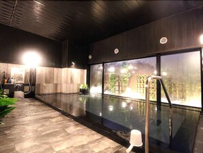 A modern indoor pool area with a glass wall, a sauna, and a wooden floor. - Hotel Route Inn Fujichuokoen Higashi (Fuji)