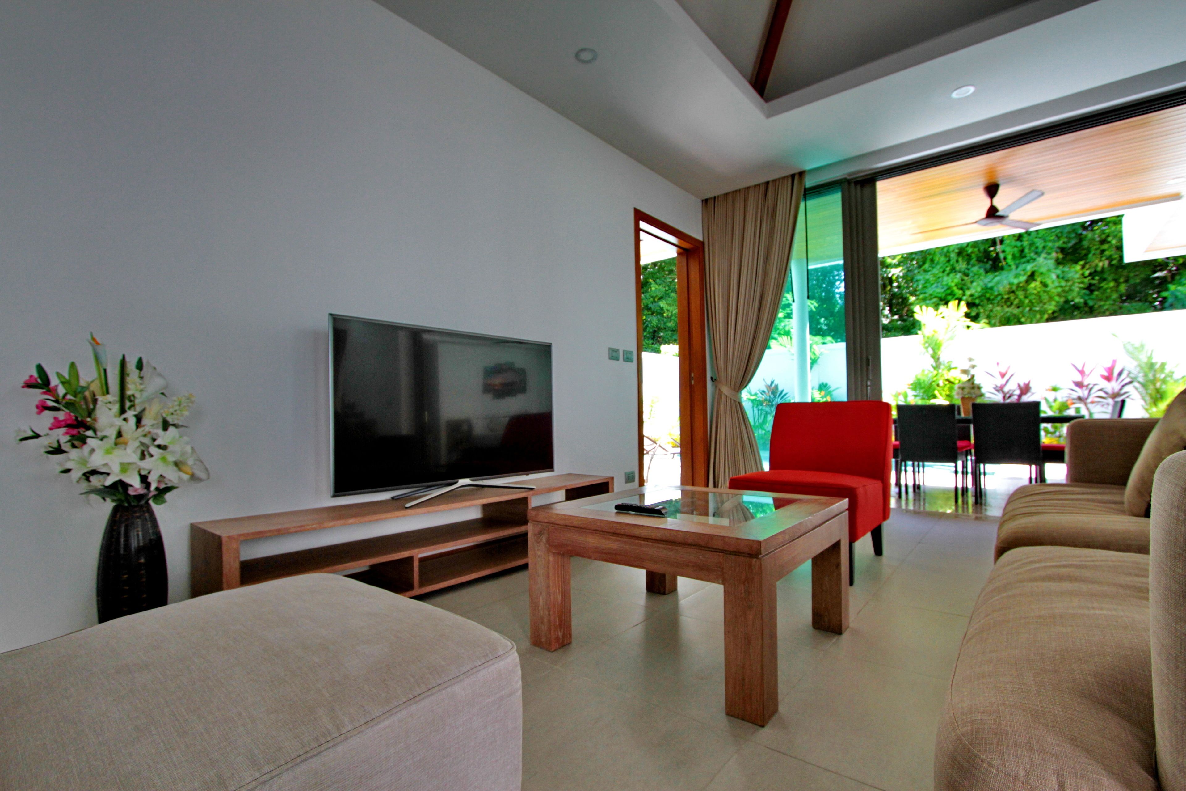 A modern living room with a flat-screen TV, wooden coffee table, and comfortable seating.