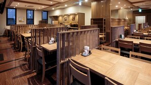 A modern restaurant with wooden furniture, high ceilings, and natural light from large windows. - Hotel Route - Inn Takaoka Ekimae (Takaoka)