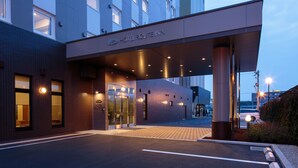 A modern hotel entrance with a covered walkway, glass doors, and a sign reading "HOTEL ROUTEINN". - Hotel Route - Inn Takaoka Ekimae (Takaoka)