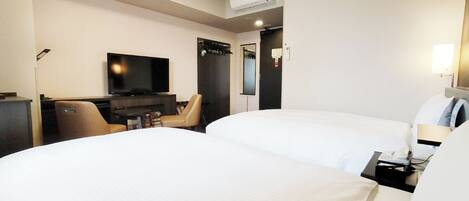 A hotel room with two beds, a TV, a desk, and a chair.