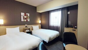 A hotel room with two beds, a desk, a chair, a small table, and a window with curtains. - Hotel Route - Inn Takaoka Ekimae (Takaoka)