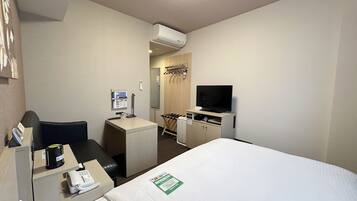 Habitación de hotel con cama, escritorio con computadora, televisor y un pequeño rincón de descanso.