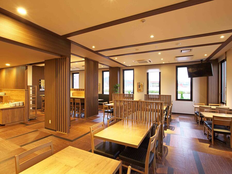 Un restaurante espacioso con mobiliario de madera, ventanas amplias y una televisión de pantalla plana.