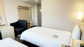 A hotel room with two beds, a desk, a chair, an air conditioning unit, and a mirror.