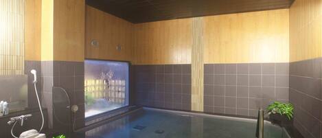 A modern bathroom with a glass-enclosed shower, wooden paneling, and a small plant.