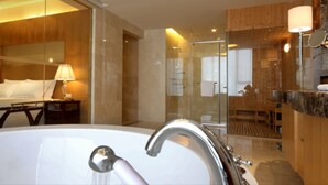 A modern bathroom with a large bathtub, a glass shower enclosure, and wooden paneling. - Hotel Paris Pan-Island (Shanwei)
