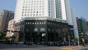 A multi-story hotel with a modern design, featuring a prominent glass facade and a corner entrance. - Hotel Paris Pan-Island (Shanwei)