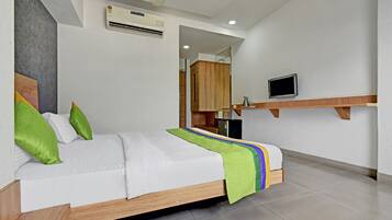 A modern hotel room with a bed, a television, and a kitchenette.