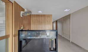 A modern kitchen with wooden paneling, a black countertop, and a ceiling fan. - Treebo Admiral Suites New Usmanpura (Chhatrapati Sambhajinagar)