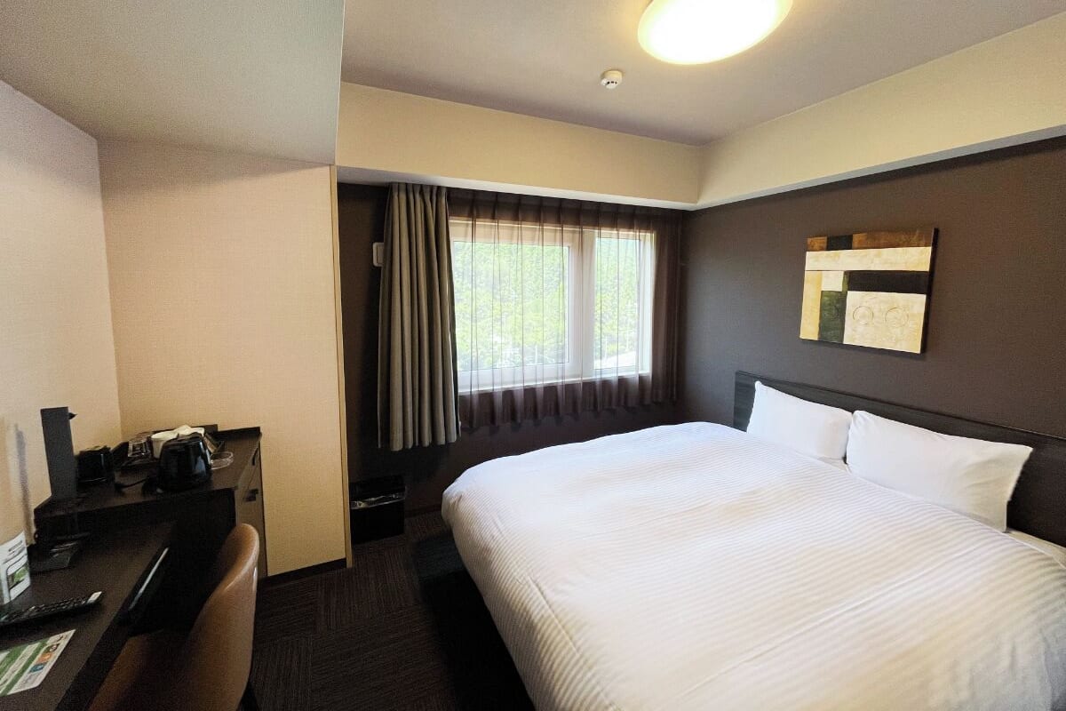 A hotel room with a bed, a desk, and a chair.