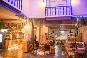 A cozy interior with a bar area, seating, and a balcony with hanging plants. - Viwo Leisure Hotel (Shanwei)