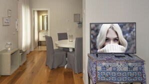 A modern living room with a dining area, a television on a table, and a patterned ottoman. - Le Dimore del Borgo (Lucca)