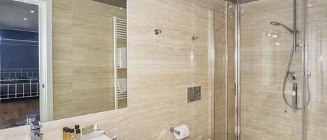 A modern bathroom with a glass-enclosed shower, a large mirror, and a white sink.