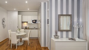 A modern kitchen with white cabinets, a microwave, and a dining area with a white table and chairs. - Le Dimore del Borgo (Lucca)