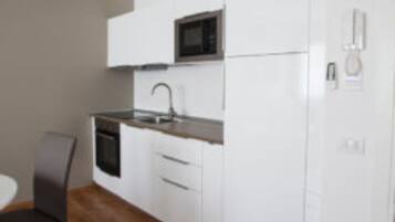 A modern kitchen with white cabinetry, a microwave, a sink, and a dishwasher.
